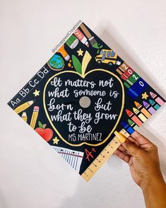 a person holding up a graduation cap with writing on it