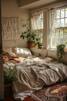 an unmade bed sitting under a window next to a potted plant on top of a rug