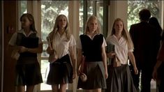 four girls in school uniforms are standing together