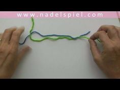 two hands are working with yarn on a piece of paper that has been stitched together