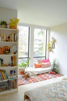 a living room filled with lots of furniture and bookshelves next to a window