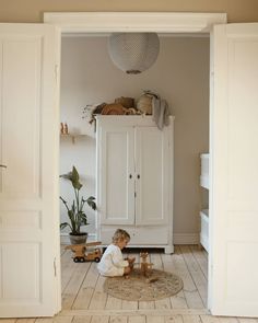 a small child playing with toys in a room that has white walls and wooden floors