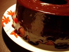 a chocolate cake sitting on top of a white plate next to a red and orange flower