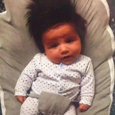 a baby sitting in a chair with a mohawk on it's head