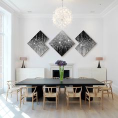 the dining room table is surrounded by white chairs and artwork on the wall above it