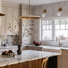 a kitchen with marble counter tops and white cabinets, along with an island in the middle