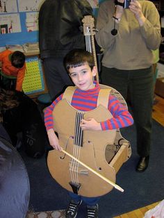 a young boy is holding an instrument and posing for the camera