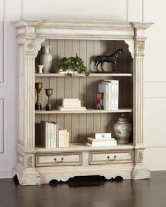 a white bookcase with books and vases on top of it in a room