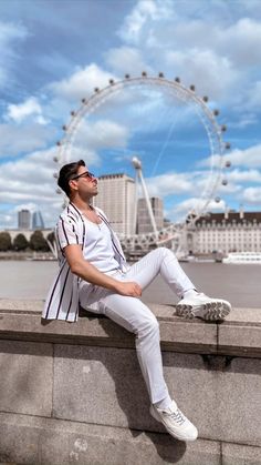 a man sitting on top of a cement wall next to a body of water with the words 4 easy poses for better photos part 1