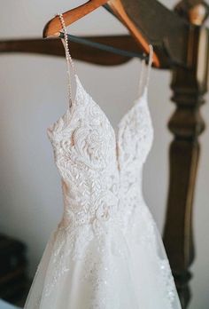 a wedding dress hanging on a wooden hanger