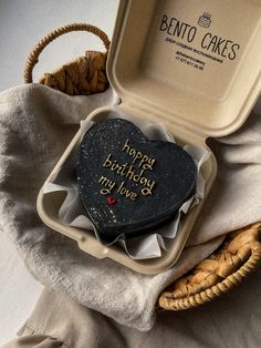 two heart shaped cookies in a box on top of a cloth covered table next to a basket