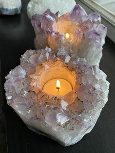 two crystal candles sitting on top of a table next to some rocks and glass vases