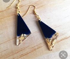 a pair of blue and gold earrings sitting on top of a wooden table