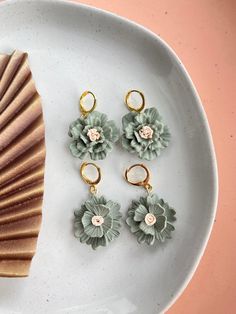 three pieces of jewelry sitting on top of a white plate next to a seashell