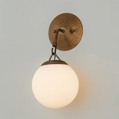 a wall light with a white ball hanging from it's side