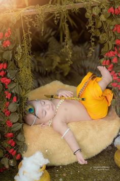 a baby laying on top of a fake fur covered ground next to flowers and plants