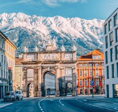 an arch in the middle of a street with mountains in the background