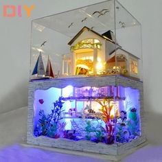 a model house is lit up with lights and fish in the aquarium tank, as well as other decorations