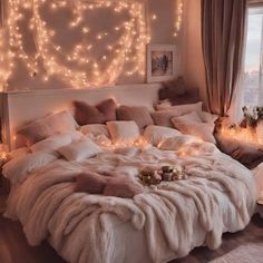 a bed with lights on the headboard and pillows in front of a large window