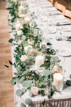 a long table with candles and greenery on it