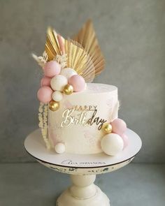 a birthday cake decorated with gold, pink and white balloons