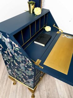 a blue desk with gold trim and flowers on it