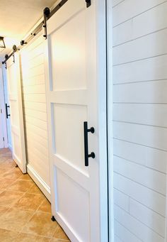 two white doors with black handles are open on the inside of a house, while another door is closed