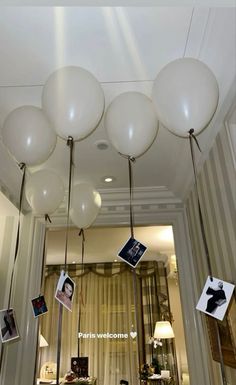 some white balloons hanging from the ceiling in front of a mirror and table with pictures on it