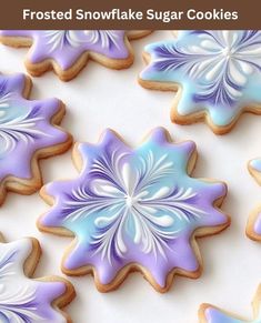 frosted snowflake sugar cookies with blue and purple icing on a white surface