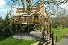 a tree house built into the side of a green field with stairs leading up to it