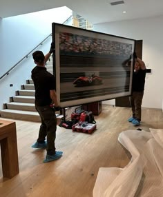 two men standing in front of a large poster on the wall next to some stairs