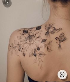 the back of a woman's shoulder with flowers and birds on it