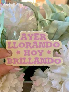 a person holding up a sticker that says ayer lornado hoy brillando