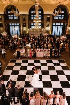 a bride and groom dance on a giant checkerboard floor at their wedding reception