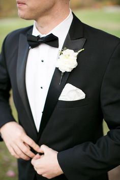 a man in a tuxedo with a white flower on his lapel collar