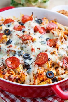 a red casserole dish with pepperoni, olives and cheese on it