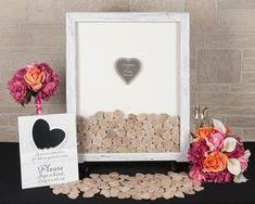 a table topped with flowers and hearts next to a framed sign that reads please save the date