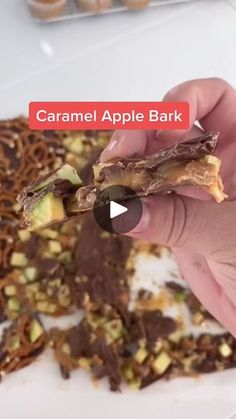 someone is holding an apple bark in front of some chocolate and pistachios