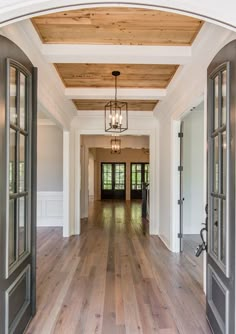 an open door leading into a large room with wood flooring and white walls on either side