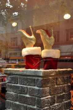 two red boots are sitting on top of a brick wall in front of a window