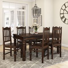 a dining room table and chairs in front of a clock on the wall above it