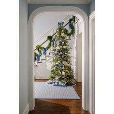 a decorated christmas tree sitting in the middle of a hallway next to a banister