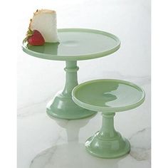 a piece of cake sitting on top of a green plate next to a slice of strawberry