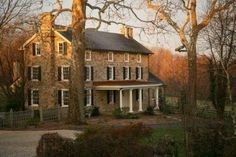 a large brick house surrounded by trees in the fall with no leaves on it's branches