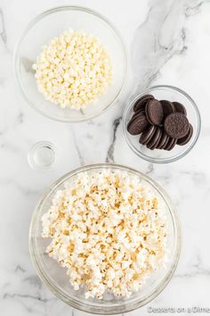 the ingredients to make oreo cookies and popcorn in glass bowls on a marble counter top