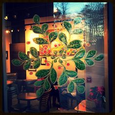 a glass window with green leaves and red berries on it, in front of a dining room table