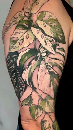 a woman's arm with green leaves and flowers on it