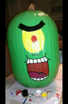 a large green pumpkin with an evil face painted on it