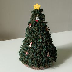 a crocheted christmas tree sitting on top of a white table next to a pair of scissors