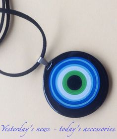 a blue and green circular pendant with a black cord on a white background that says victory news today's accessories